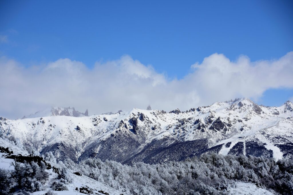 Stunning snowy mountains under a bright blue sky in Bariloche, Argentina.
