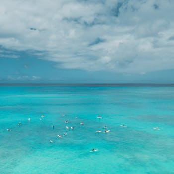 Drone shot of surfers on turquoise waters in Hawaii under a cloudy sky. Perfect summer scene.