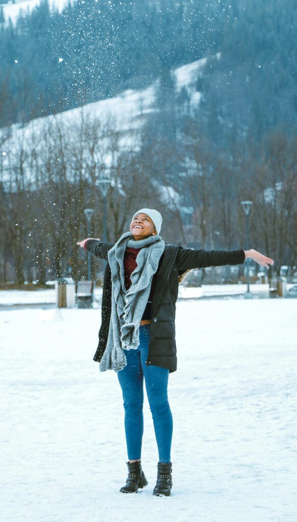 A woman with arms outstretched enjoys a snowy winter day in bariloche argentina