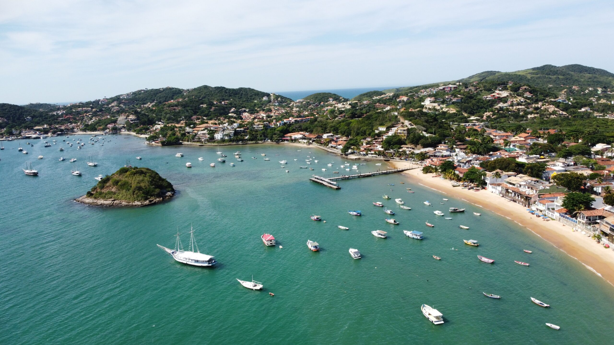 Aerial view of Buzios Bay, RJ, Brazil showcasing boats, pier, and lush green landscape.