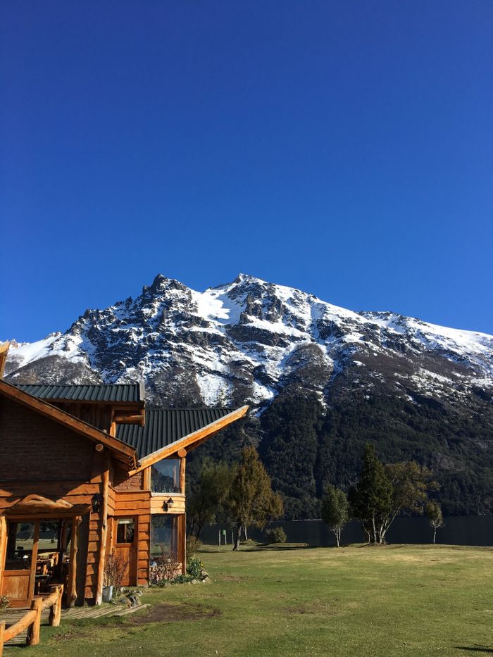 Charming wooden cottage with snowcapped mountain backdrop in Mendoza Province, Argentina.