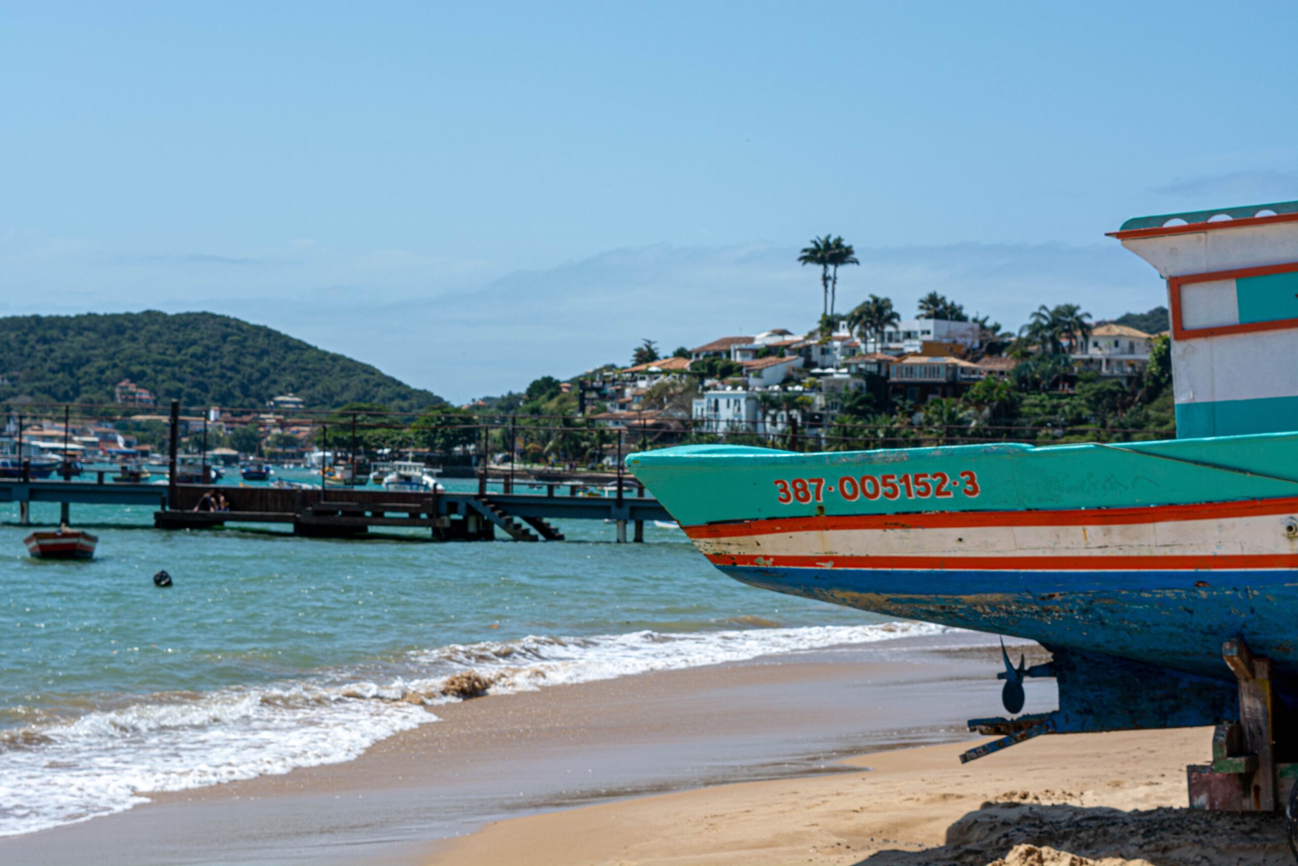 Colorful boat on the beach of Armação dos Búzios, Brazil, with scenic ocean view.